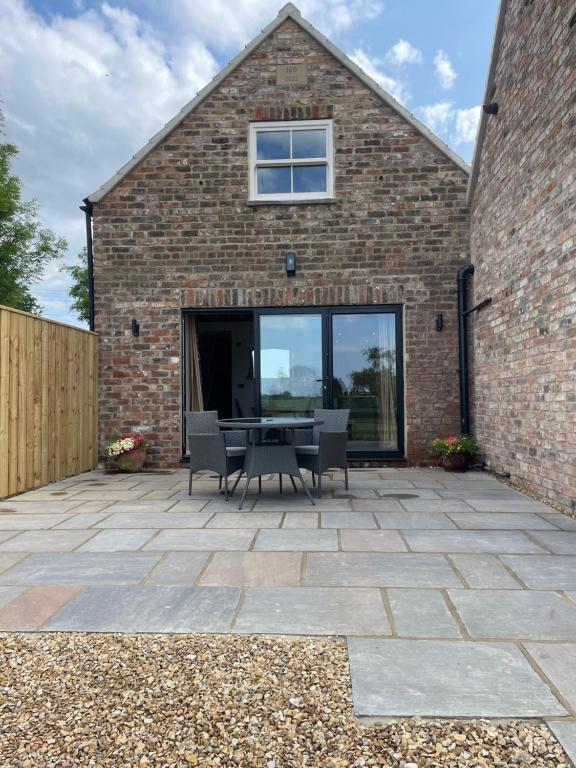 Converted Bullamoor Barns, Northallerton في نورثاليرتون: فناء مع طاولة وكراسي أمام مبنى من الطوب