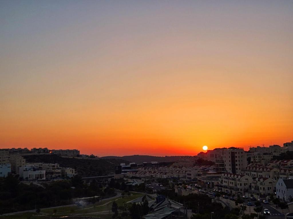 a sunset over a city with the sun setting at פנטהאוז ברמה in Bet Shemesh