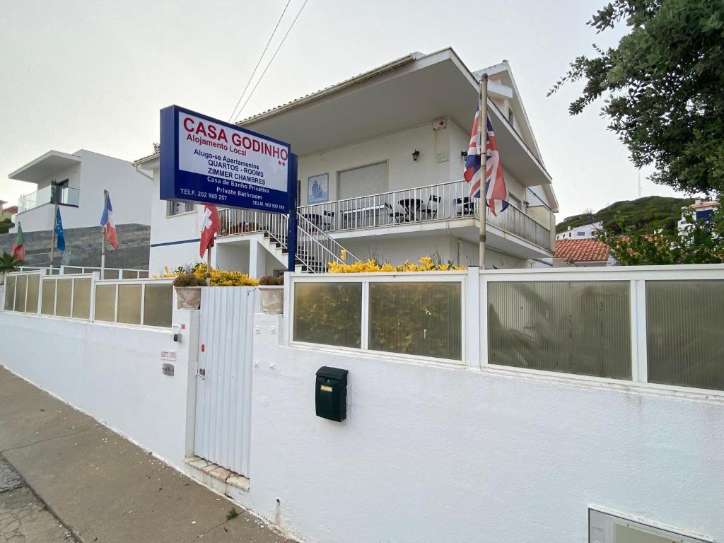 a white house with a sign in front of it at Casa Godinho in São Martinho do Porto