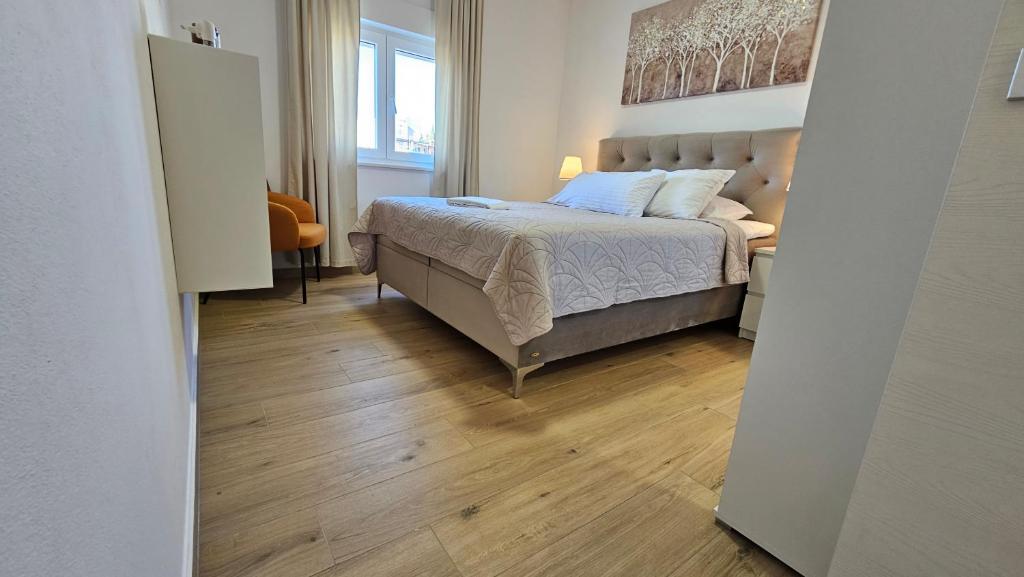 Schlafzimmer mit einem Bett und Holzboden in der Unterkunft Eximius Apartment in Pula