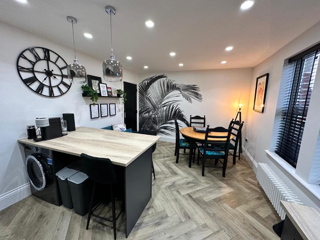 a kitchen and dining room with a table and a clock at 3a Roman View, beautifully appointed apartment in Roundhay, sleeps up to 6, bedrooms with en suite bathrooms, EV charging in Moortown