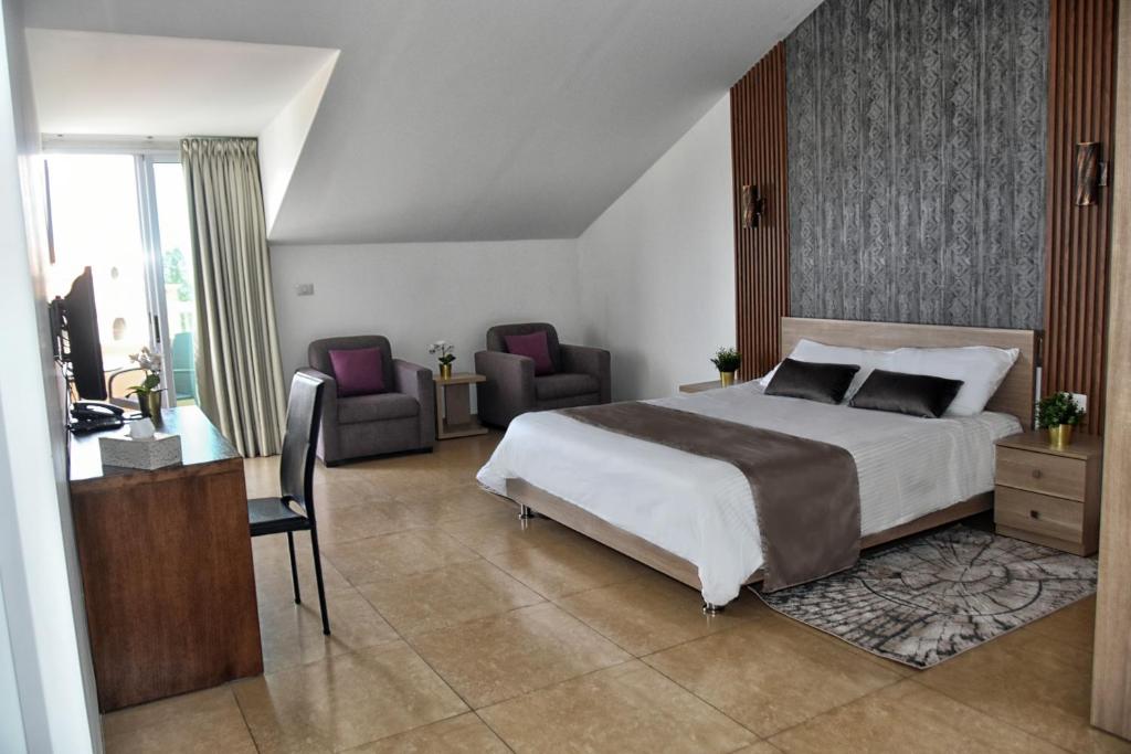 a bedroom with a bed and a desk and chairs at Byblostar Hotel in Jbeil