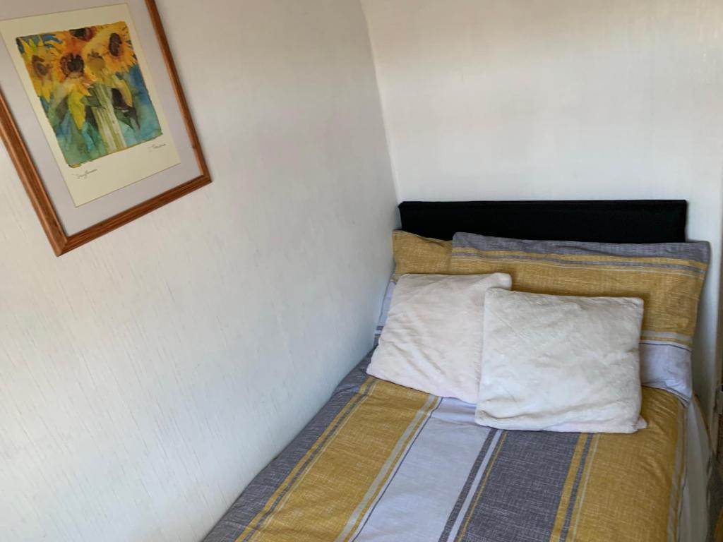 1 cama con 2 almohadas y una foto en la pared en Hadfield Avenue en Hoylake