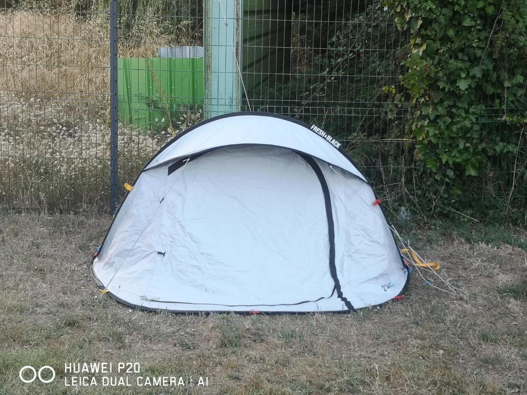 a white tent sitting in the grass next to a fence at tente pour 2 personnes in Saint-Jean-de-Monts