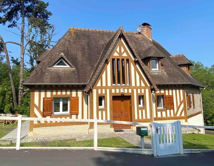 une maison avec une clôture blanche devant elle dans l'établissement La maison de Carla, à Villers-sur-Mer