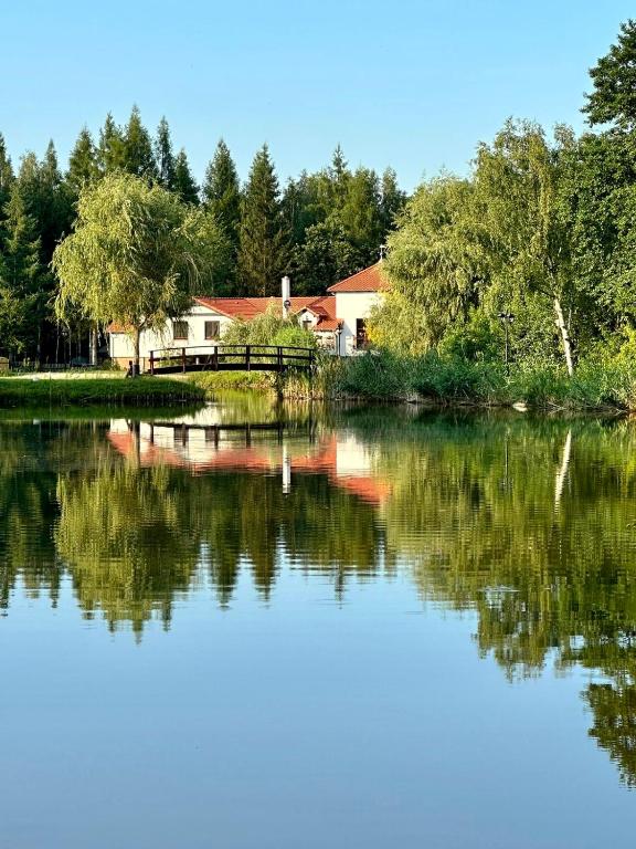 a view of a lake with a house in the background at Osada Gęsin in Zabór