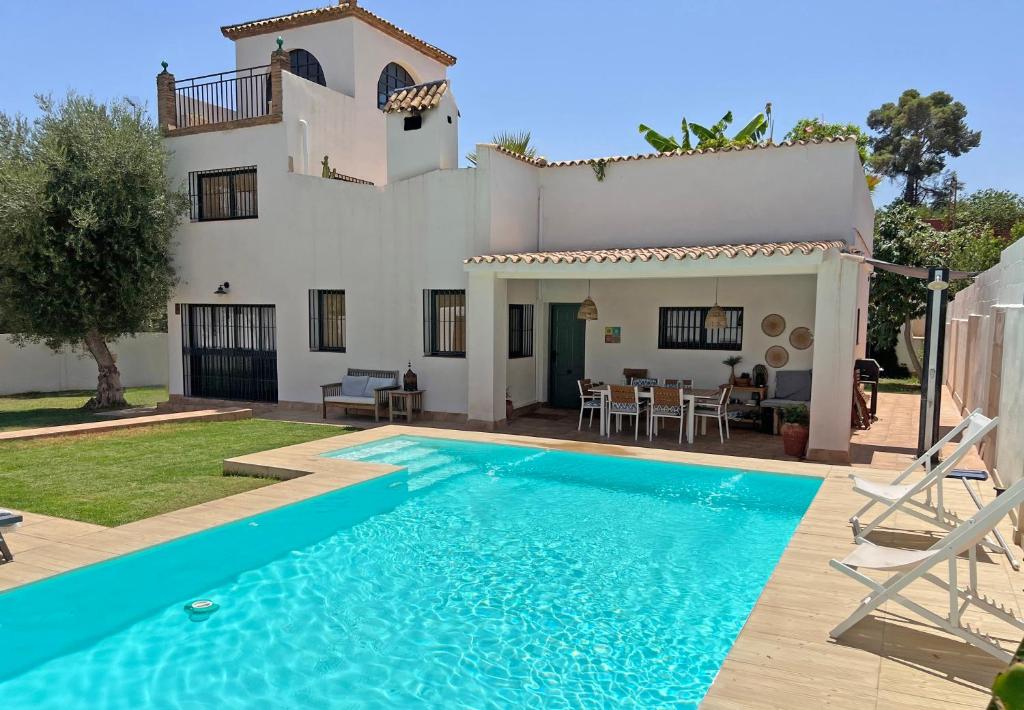 a villa with a swimming pool in front of a house at Chalet con encanto cerca de Sevilla in Alcalá de Guadaira