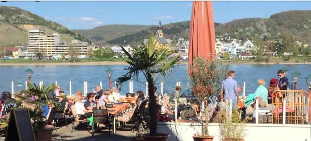 a group of people sitting at tables near a body of water at Hotel Rheinischer Hof in Bad Breisig