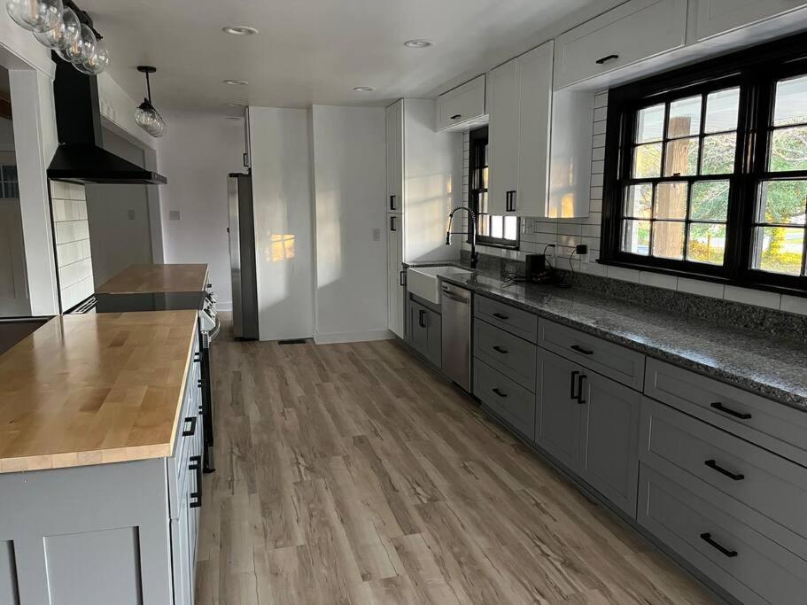uma grande cozinha com armários brancos e pisos de madeira em Newly renovated rancher with yard and garage! Furnished! em Williamsburg