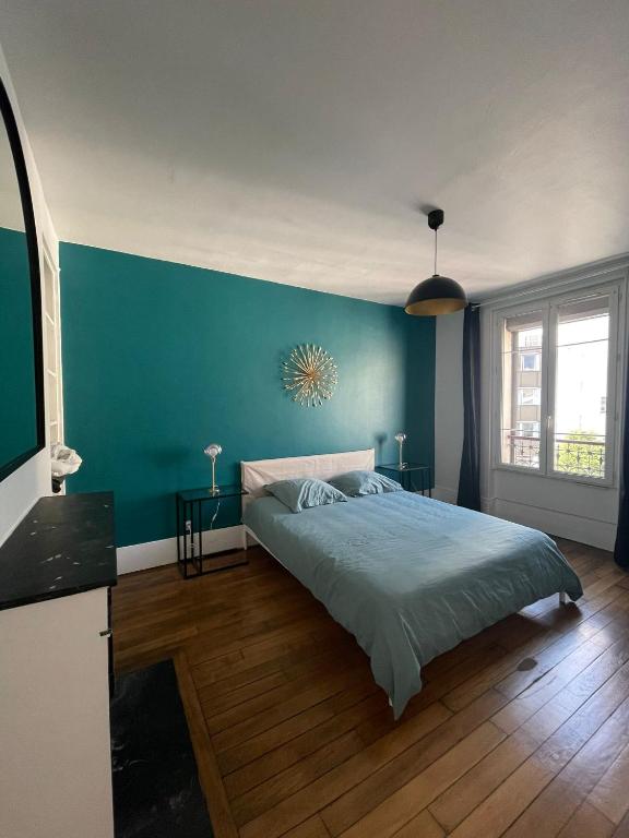 une chambre avec un lit et un mur bleu dans l'établissement Paris Eiffel Flats, à Paris