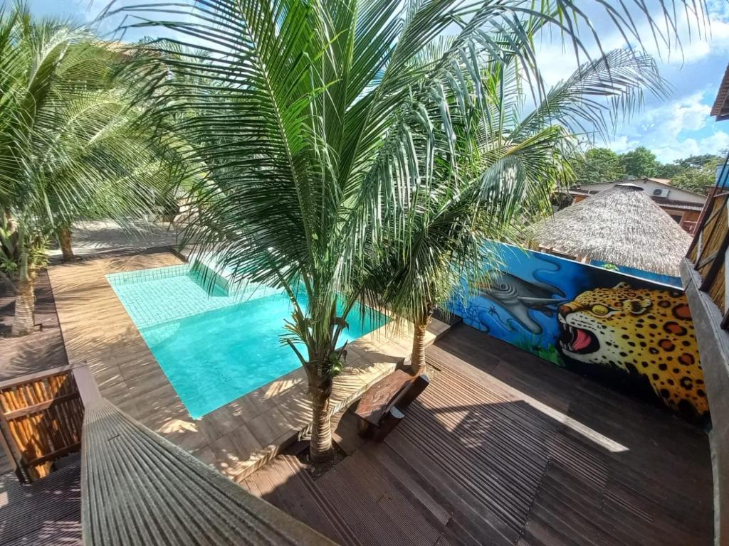 a resort with a palm tree and a swimming pool at Pousada Tupaiú in Alter do Chao