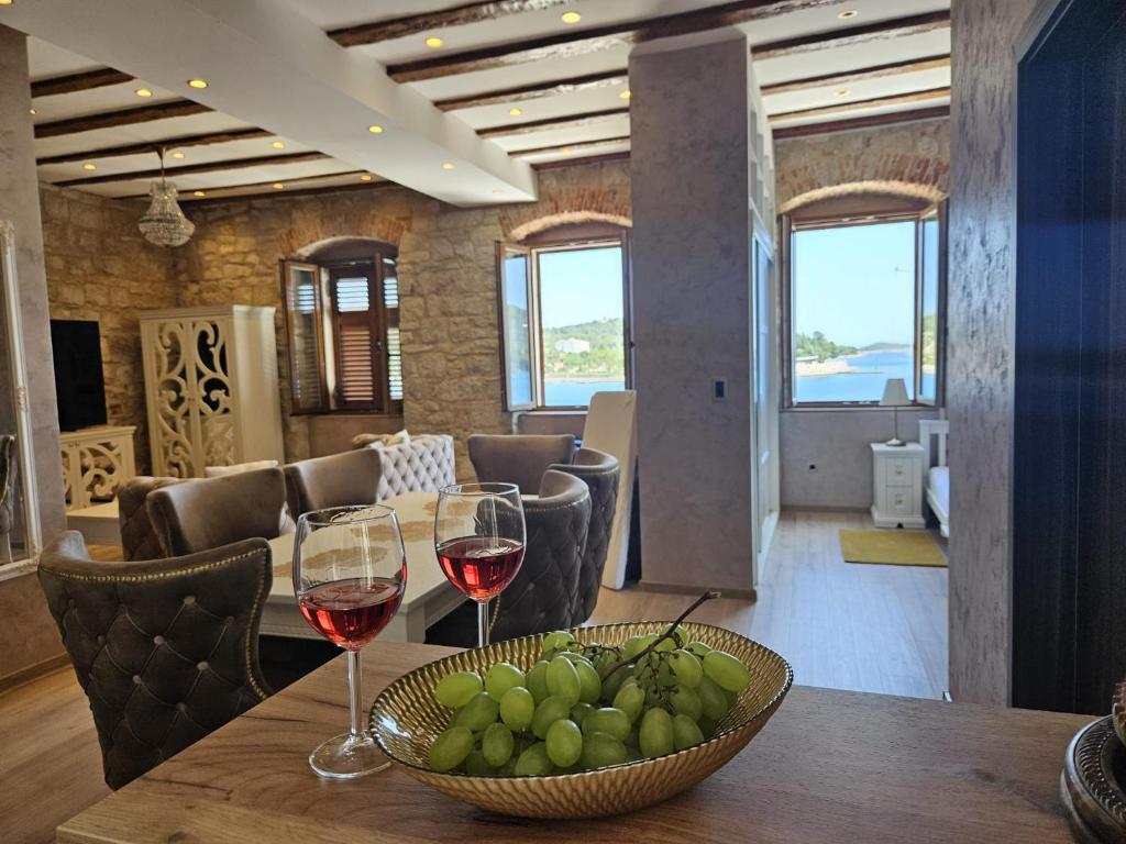 a table with two glasses of wine and a bowl of fruit at Luxury Seafront Suite Fabri in Vis