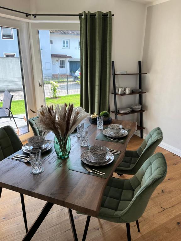 uma mesa de jantar em madeira com cadeiras verdes e uma mesa em UNiQE I 90qm I Terrasse em Rosenheim