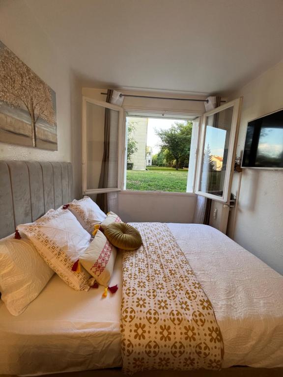1 dormitorio con cama con almohadas y ventana en Studio situé à 5 min du château de Versailles et stationnement gratuit en Versailles