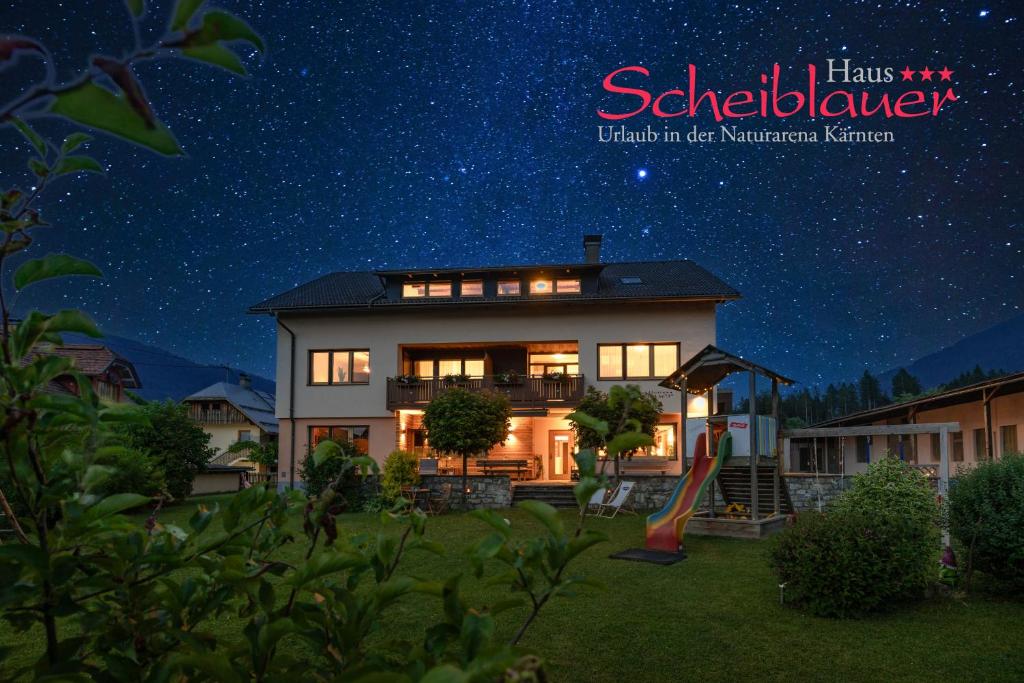 une maison avec un ciel étoilé la nuit dans l'établissement Haus Scheiblauer, à Tröpolach