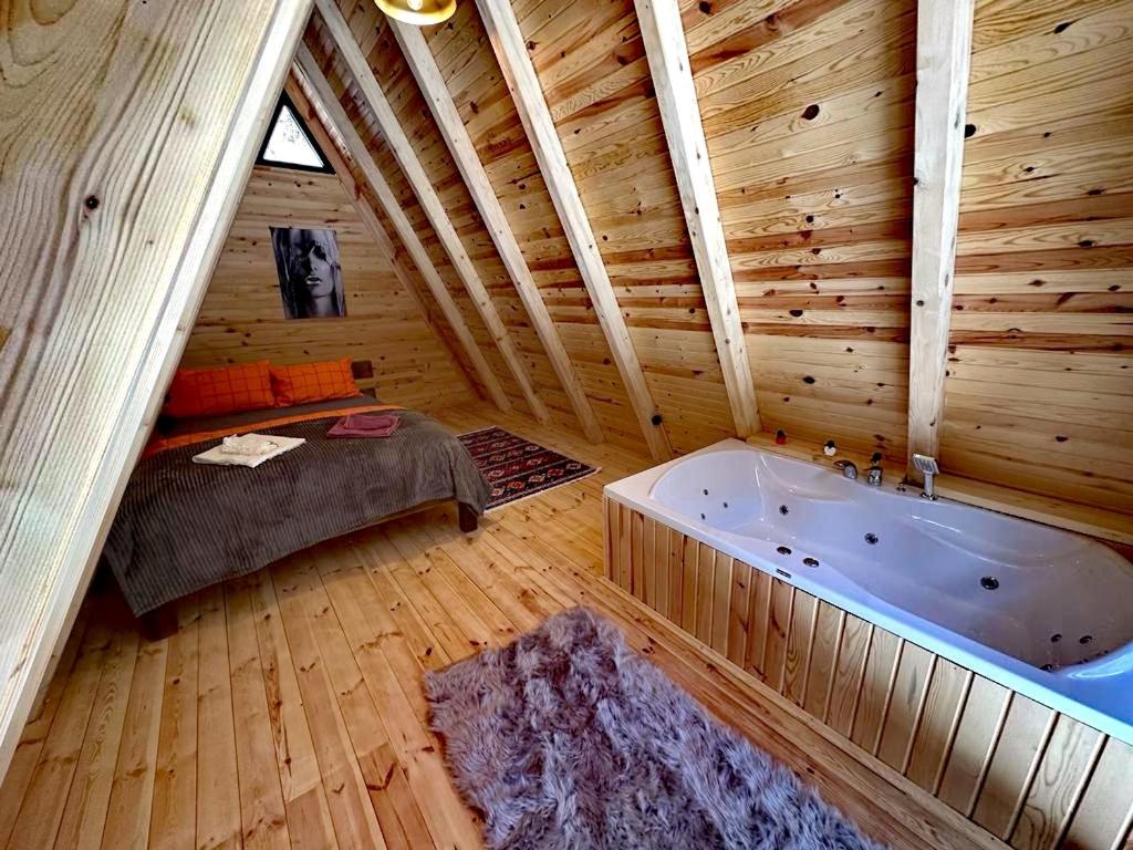 a attic room with a tub and a bed in it at Mariposa Bungalov in Ayder Yaylasi