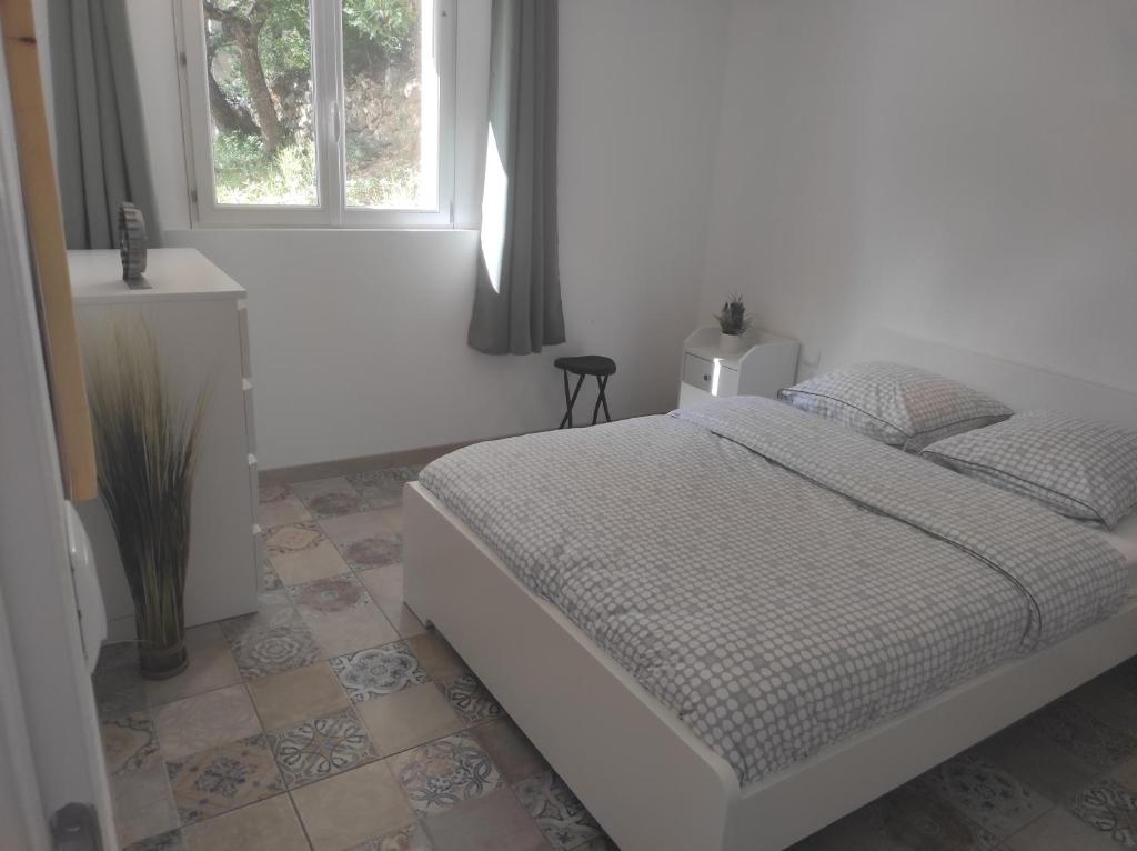 a white bedroom with a bed and a window at Les quatre chênes in Bauduen