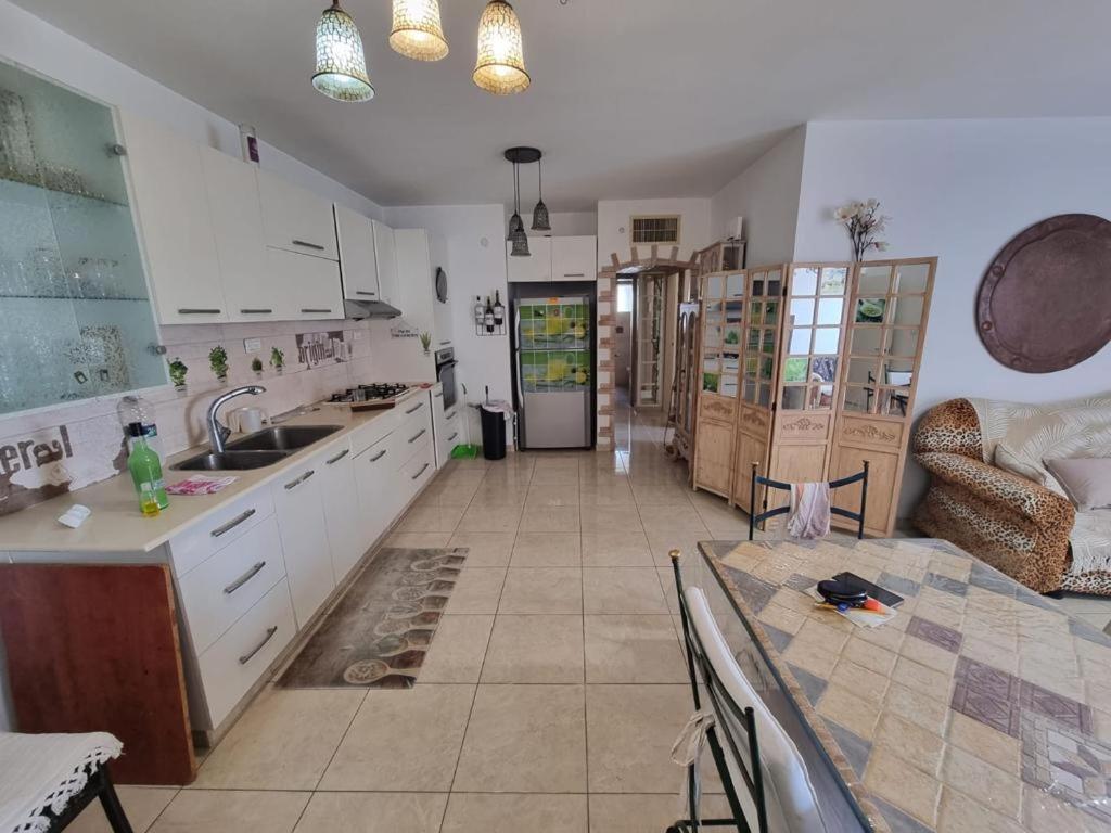 a large kitchen with white cabinets and a table at Charming Warm and Sun-Filled 1 and 2 Bedroom Apartment in Ashdod