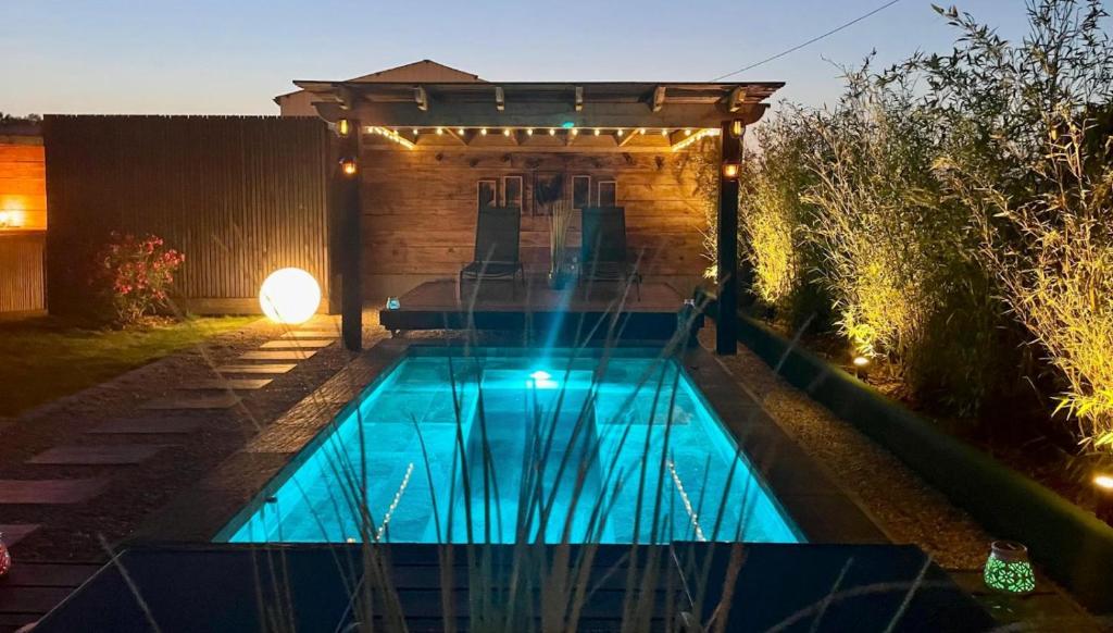 a small swimming pool in a backyard at night at Idyllique Studio PiscineSPA, Sauna au jardin tropical in Jouarre
