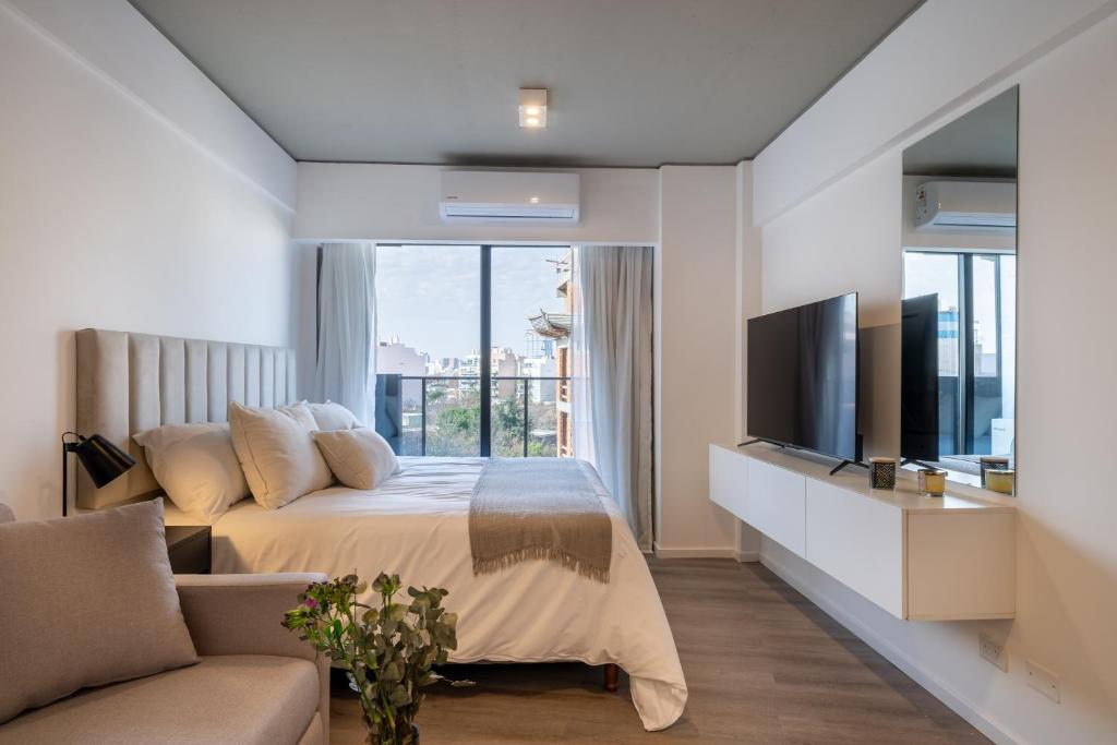 Un dormitorio con una cama, un televisor y un sofá. en La Vie Suite Palermo Hollywood, en Buenos Aires