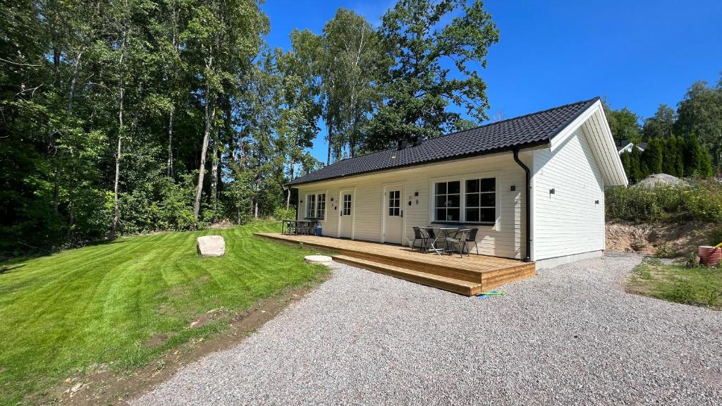 a small white cabin with a porch and a deck at Villa sjöviken 24 in Kolmården