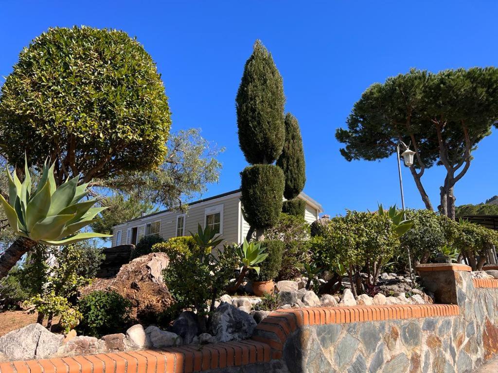 a garden in front of a house with trees and bushes at Chalet - Casa móvil Pinos - 3 beds, pool, private garden in Alhaurín de la Torre