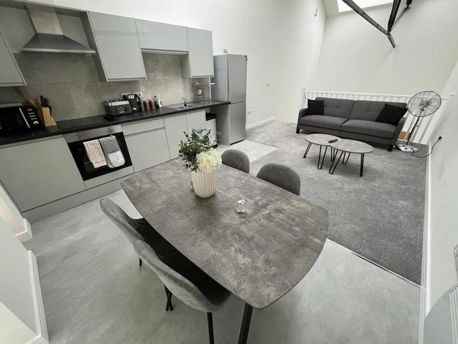 a kitchen and living room with a table and a couch at Modern Loft Apartment in Rotherham