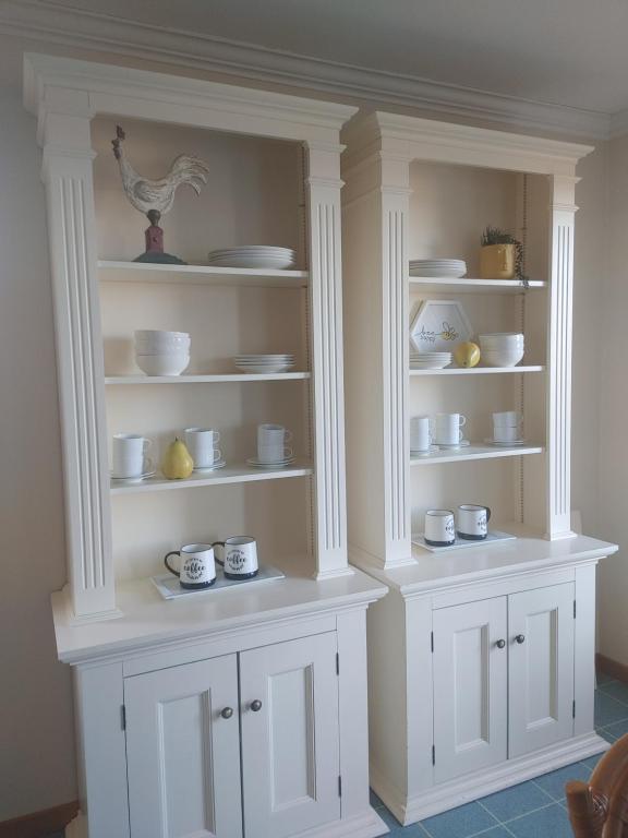 a white hutch with cups and dishes on it at Vinegar Hill Airbnb in Bridgetown