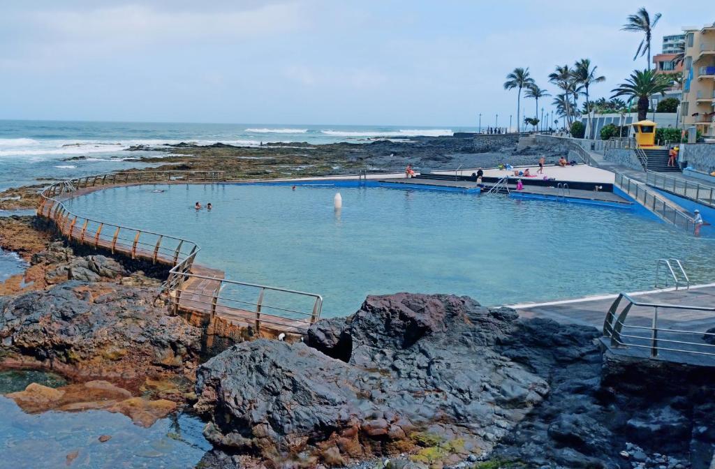 - une piscine avec des hommes à côté de l'océan dans l'établissement Vivienda Vacacional El Roquete, à Punta del Hidalgo