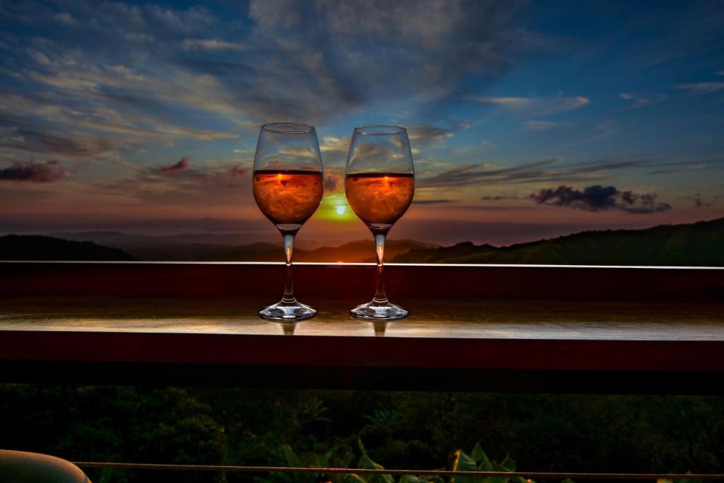 two glasses of wine sitting on a window sill with the sunset at Casa Zafiro in Monteverde Costa Rica