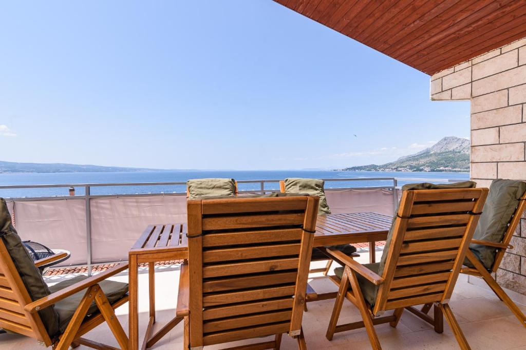 een tafel en stoelen op een balkon met uitzicht op de oceaan bij Villa Del Mar Omiš in Omiš