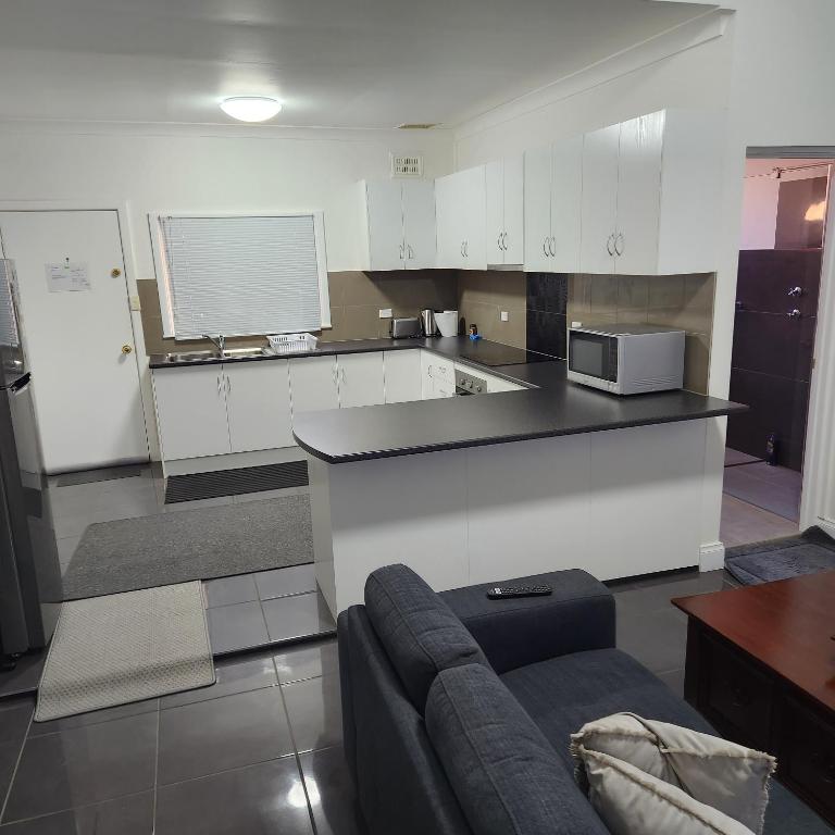 ブロークンヒルにあるCity Villa 39 Blende st Broken Hill NSW 2880の白いキャビネットとソファ付きのキッチンが備わります。