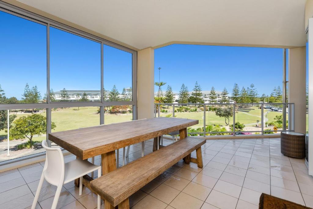 a dining room with a wooden table and chairs and large windows at Wave Culture 1204 Beach Bliss - Apartment with complex Pool & Spa in Kingscliff