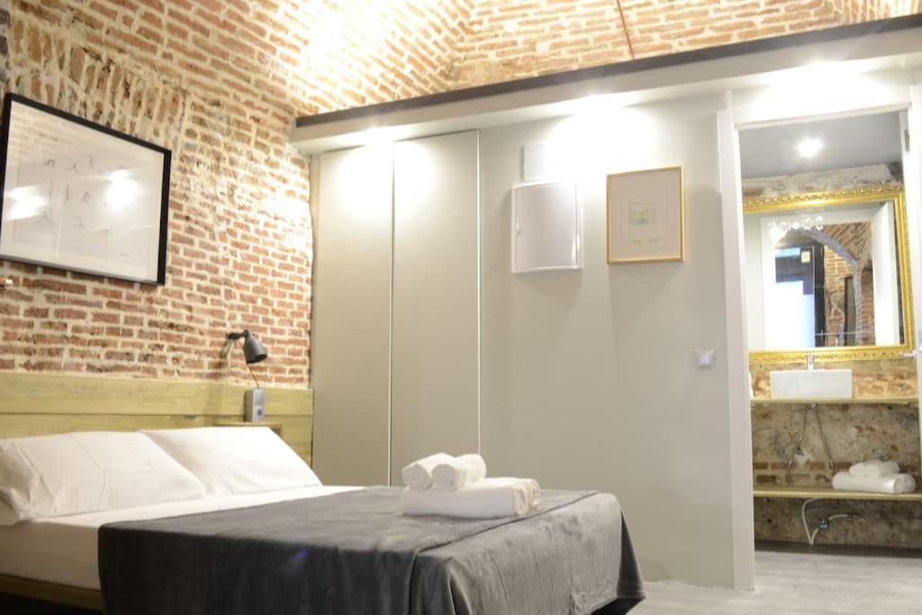 sypialnia z łóżkiem i ceglaną ścianą w obiekcie Cozy Loft - Royal Palace w Madrycie
