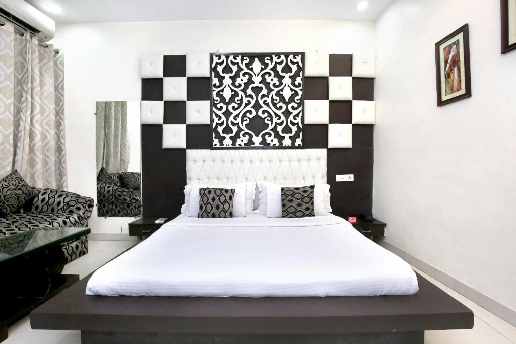 a bedroom with a bed with a black and white headboard at Capital O Hotel Nayyar in Amritsar