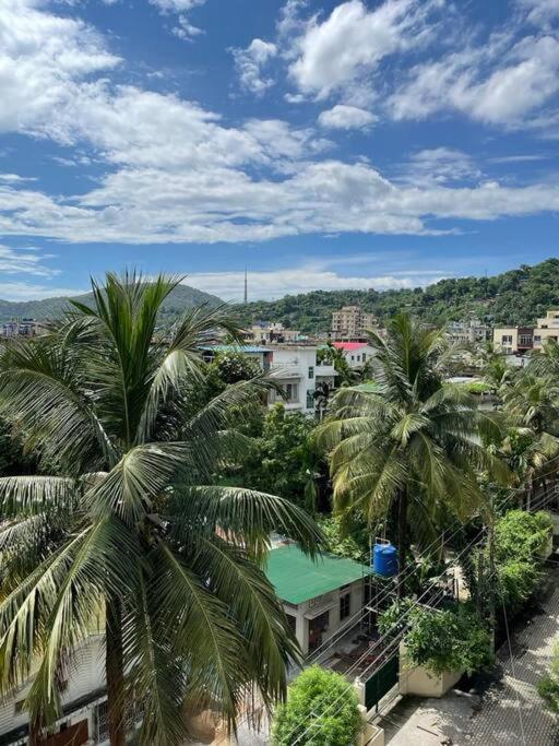 a view of a city with palm trees and buildings at Hrishi's Terrace Home. in Guwahati