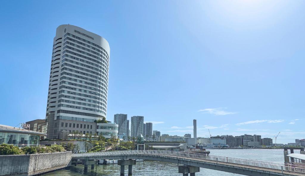 東京的住宿－東京灣洲際酒店，一座高大的建筑,靠近一条有桥的河流