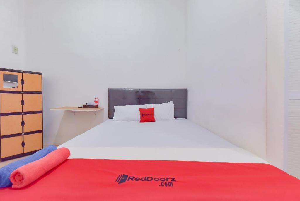 - une chambre avec un grand lit blanc et une couverture rouge dans l'établissement Reddoorz near Juwata Airport Tarakan, à Tarakan