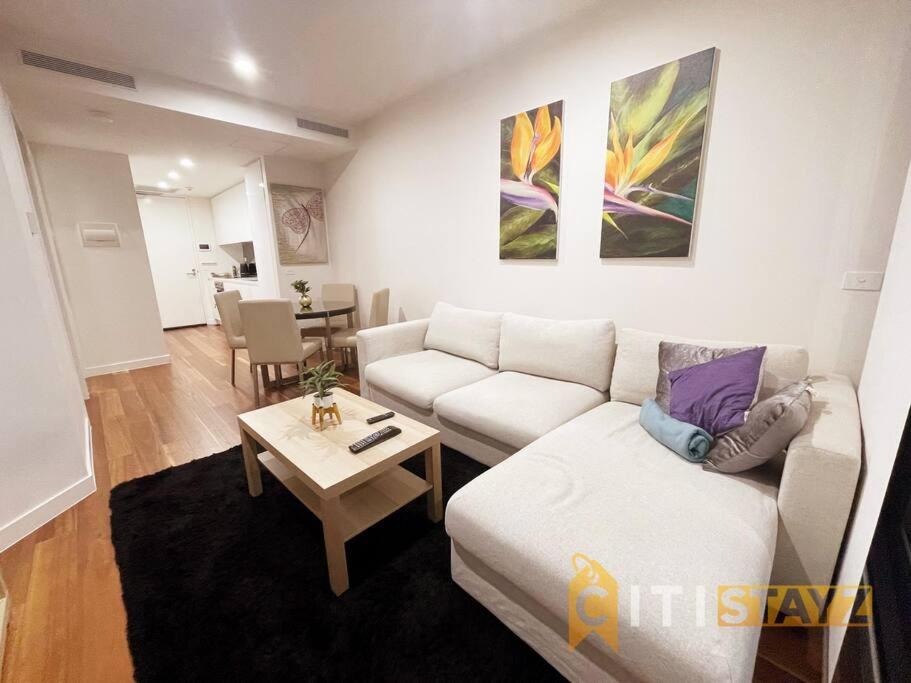 a living room with a white couch and a table at Braddon Bliss - Modern 1Bd 1Bth Haven in Canberra