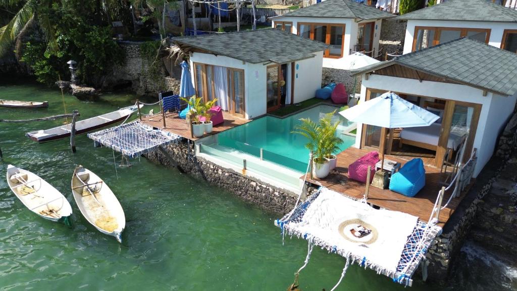 a house with a pool and a boat in the water at Indigo Blue Ceningan in Nusa Lembongan