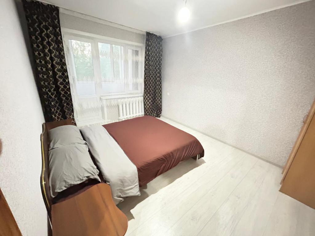 - une chambre avec un lit et une fenêtre dans l'établissement 2 комнатная квартира магазин Айналайын по Ауельбекова, à Kökşetaw