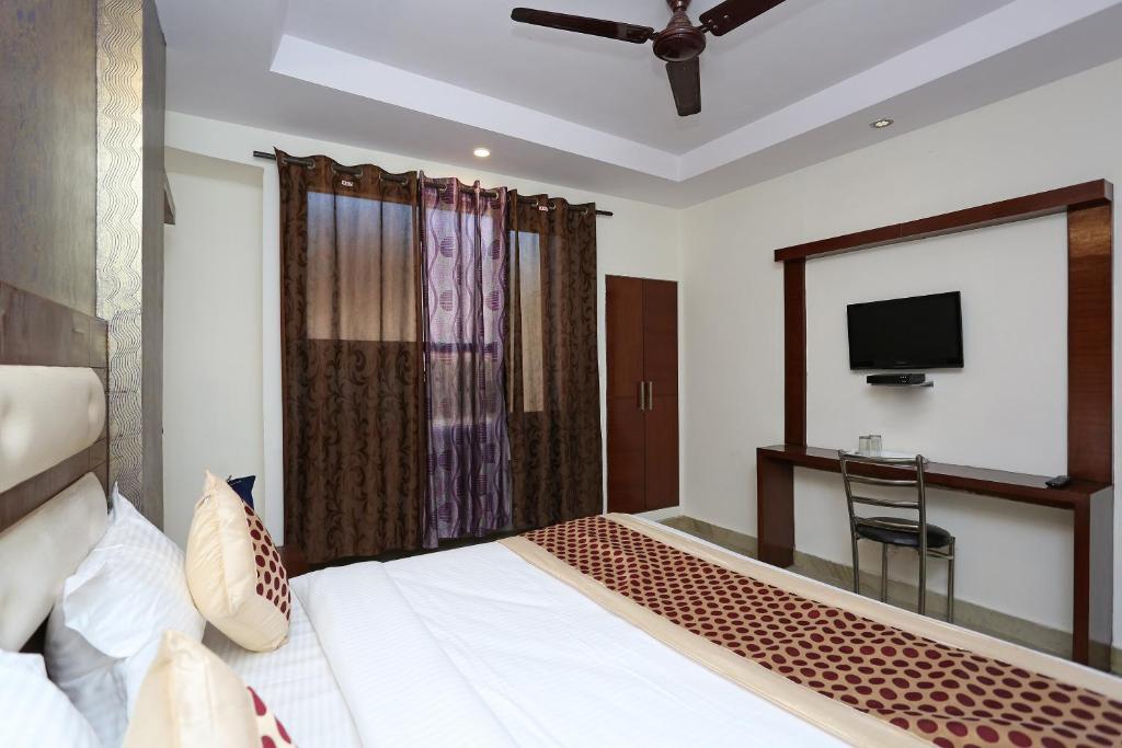 Cette chambre comprend un lit et une télévision. dans l'établissement OYO Hotel Repose Villa Near Gurudwara Shri Bangla Sahib, à New Delhi