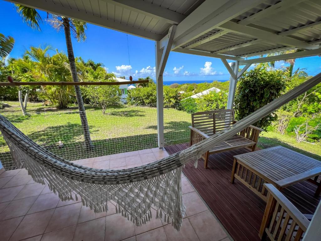 a hammock on a porch with a view of the ocean at Gîte Côté Mer - Vue mer in Grand-Bourg