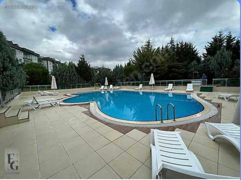 a large swimming pool with white chairs at İstanbul Sabiha Gökçen 2 plus 1 near to Sabiha Gokcen Airport in Istanbul