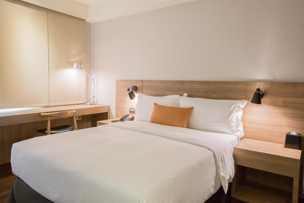 a bedroom with a large white bed with a wooden headboard at Just Sleep Kaohsiung Zhongzheng in Kaohsiung