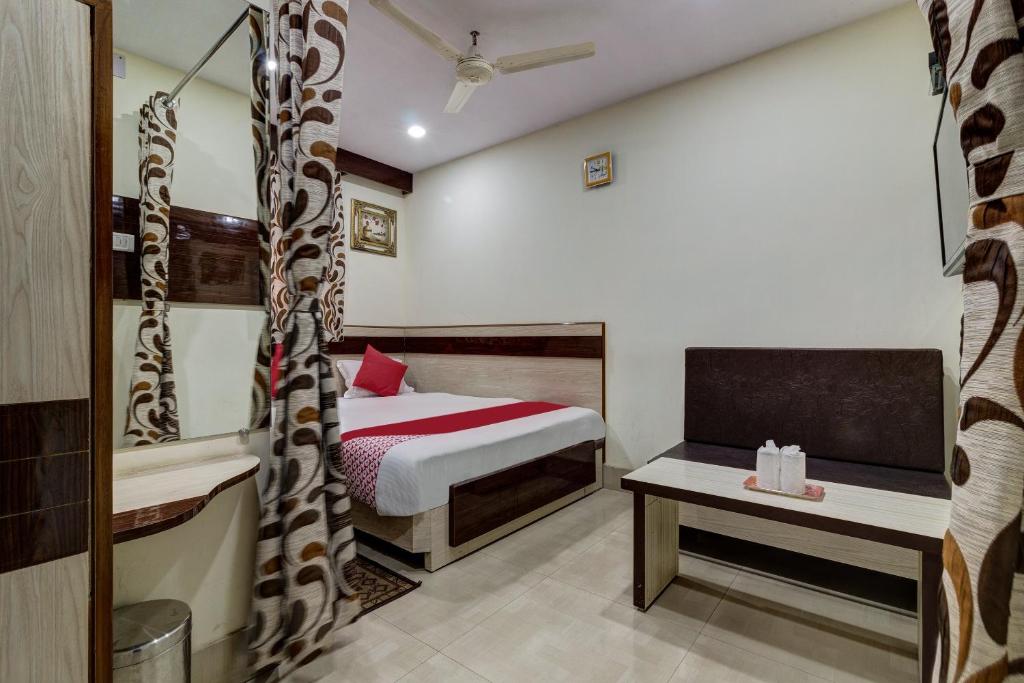 ein Schlafzimmer mit einem Bett und einem Tisch in einem Zimmer in der Unterkunft OYO Hotel Satguru in Jamshedpur