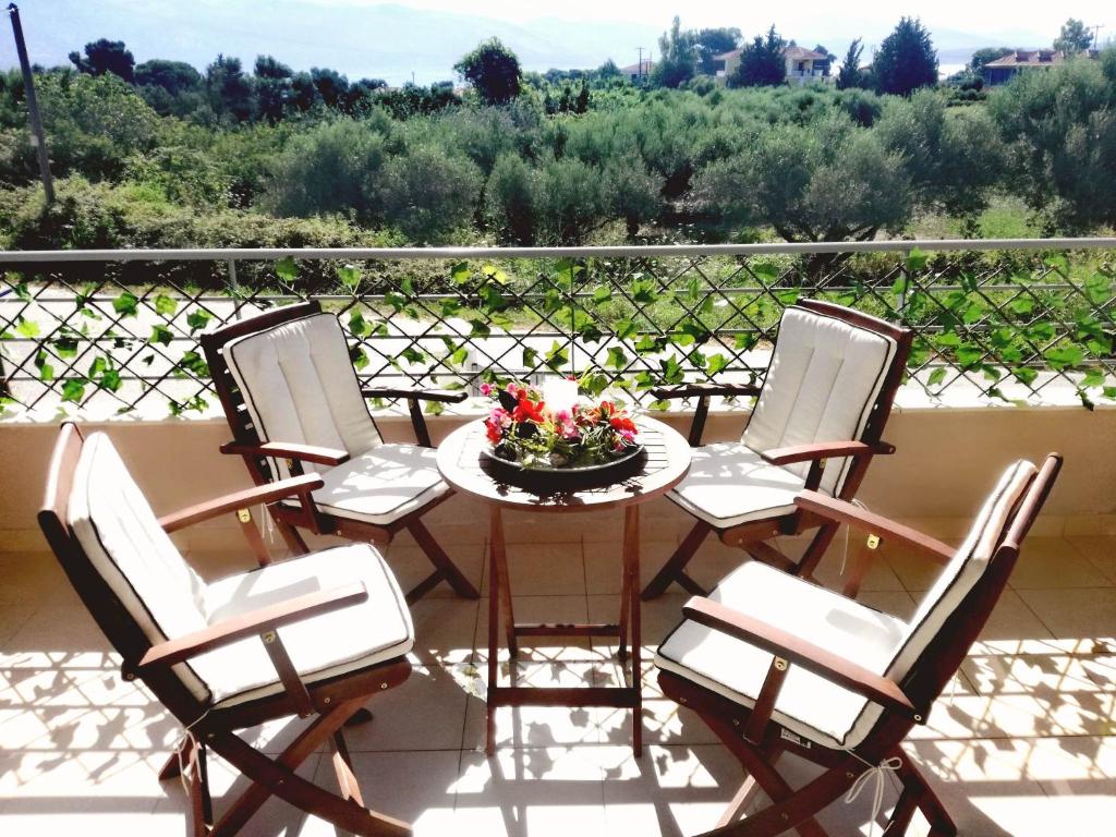 - une table avec des chaises et un bol de fleurs sur le balcon dans l'établissement VISTA DI MARE, à Lixouri