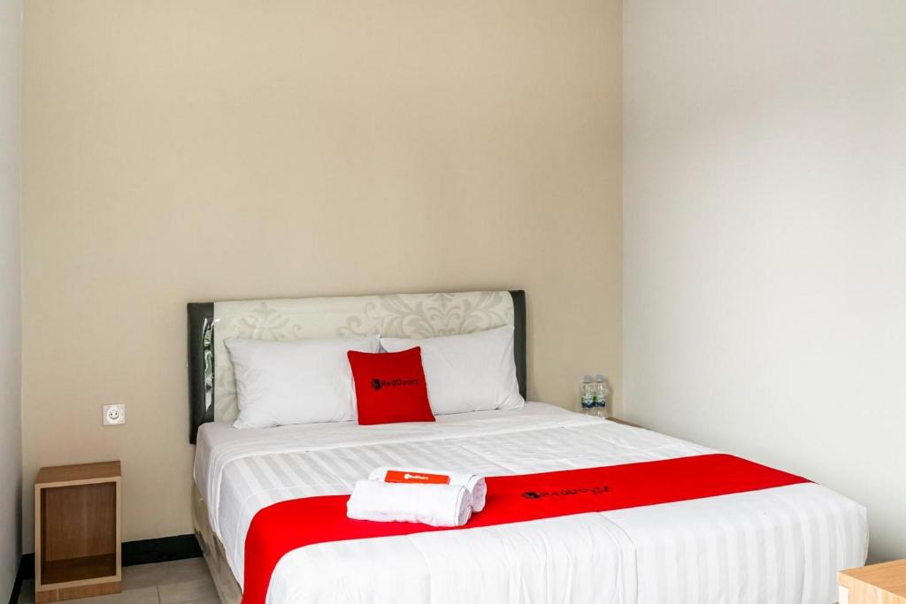 a bedroom with a bed with a red pillow on it at RedDoorz near Puri Indah Lippo Mall 2 in Jakarta