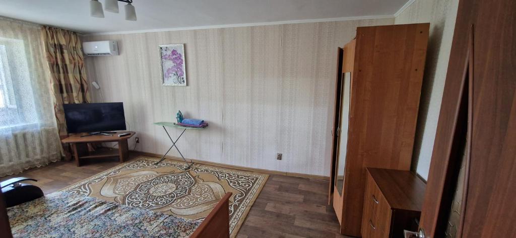 um quarto com uma cama e uma televisão em Однокомнатная квартира в Караганде em Karaganda