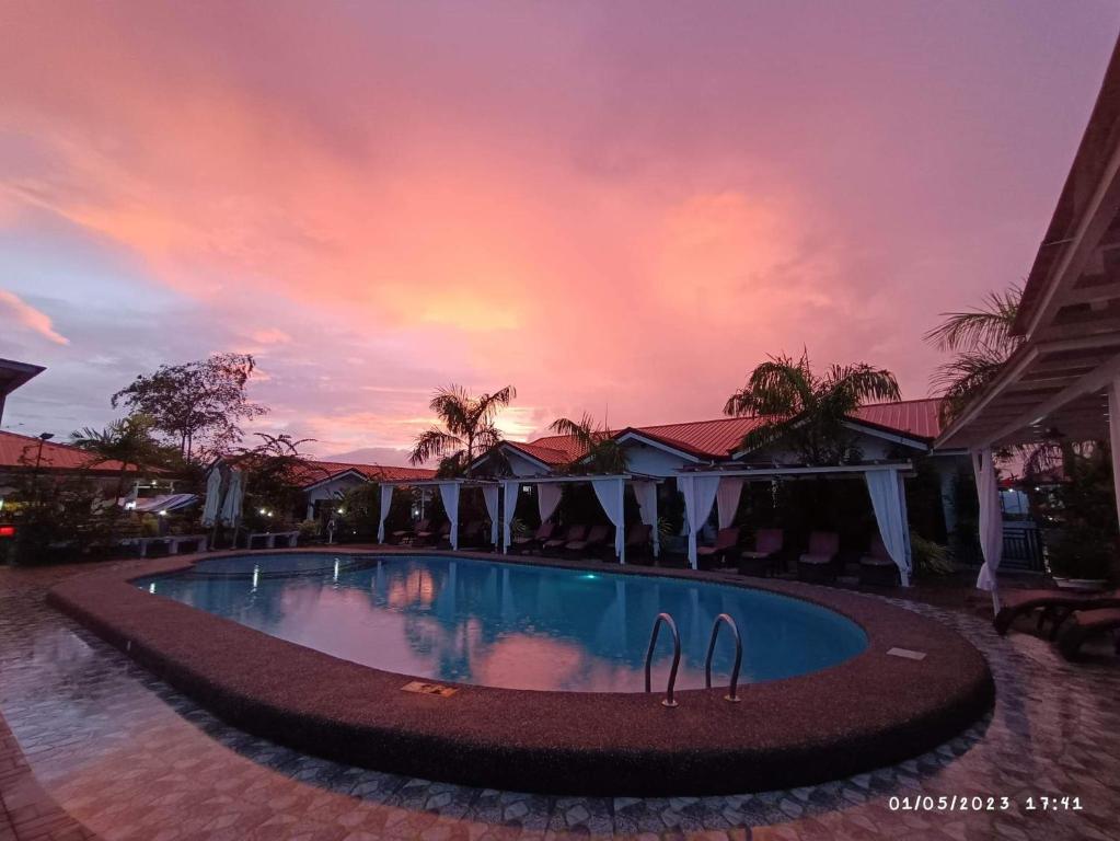 a swimming pool with a sunset in the background at Garden Village Resort in Moalboal